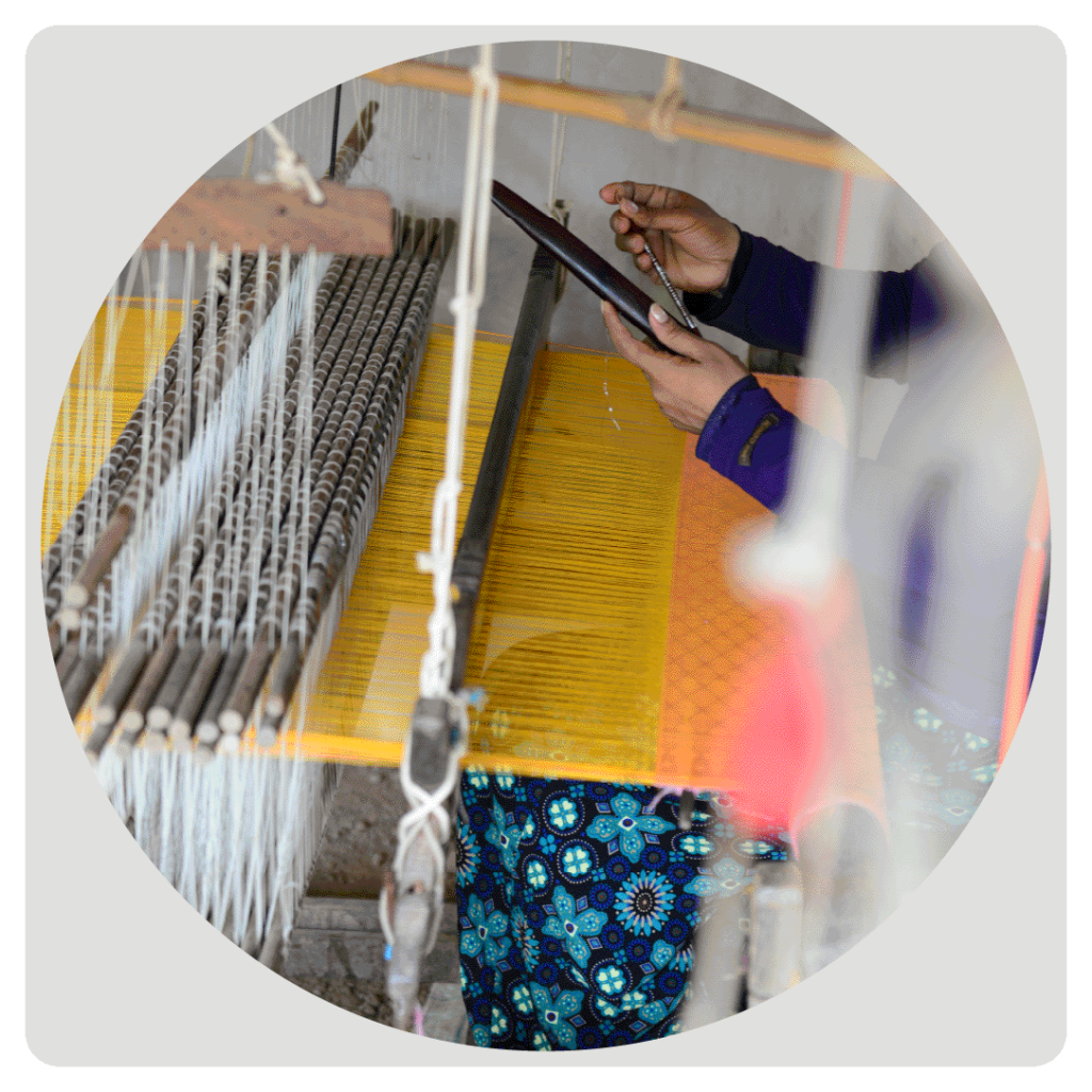 Interwoven Blog cover image - photo of a person sitting at a loom completing a weaving project