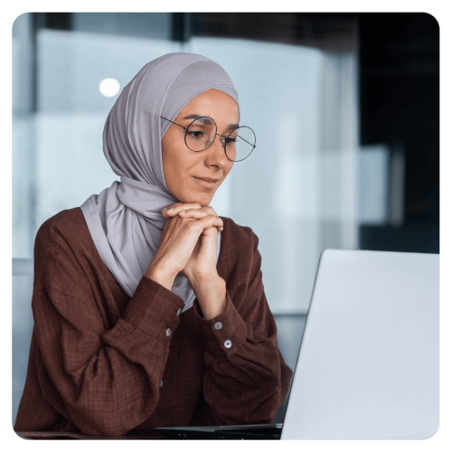 Woman with glasses and hijab looking at her laptop